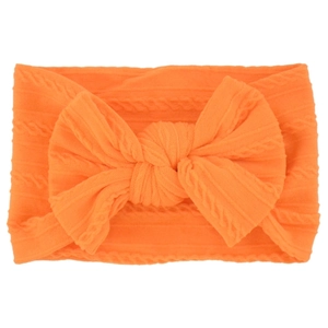 Close-up of orange knitted baby headband featuring a large soft bow and jacquard texture