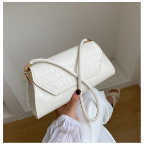 Close-up of white crocodile pattern shoulder bag with elegant gold metal hardware