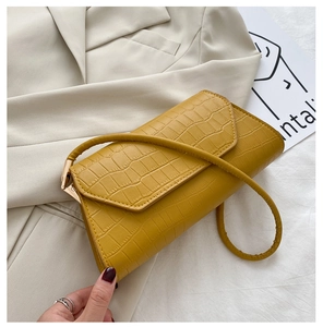 Detail of yellow crocodile pattern leather handbag with gold metal hardware