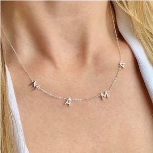 Macro view of sterling silver MAMA pendant necklace worn on a woman's collarbone