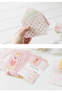 Close-up of pastel floral and plaid scrapbooking paper on a clean wooden desk