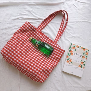 Detail shot of red gingham canvas tote bag with long handles on a white fabric background