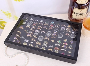Top view of 100-slot black ring display box with transparent lid and luxury props