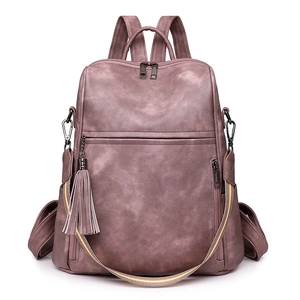 Detail view of dusty pink retro backpack featuring woven strap and tassel charm