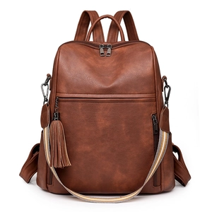 Close-up of brown vintage leather backpack with fringe detail and striped strap