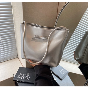 Close-up of silver PU leather tote bag with a decorative bow and metallic finish texture