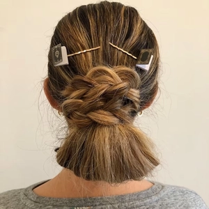 Miniature book bobby pins for book lovers on a braided bun hairstyle for women