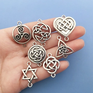 Hand holding silver Celtic knot connector charms for DIY bracelet and jewelry making