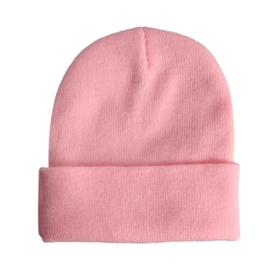 Close-up of bright pink knitted beanie showing soft acrylic yarn texture and ribbed cuff