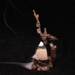 Détail macro du brûle-encens avec oiseau sur branche de prunier et fumée fluide