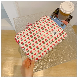 Quilted white laptop sleeve with red tulip patterns and a pink zipper detail