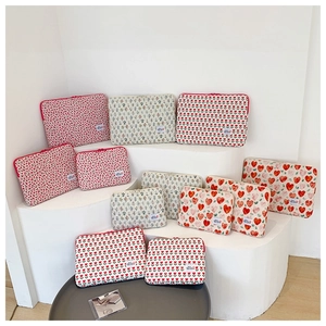 Quilted laptop sleeves with floral and heart prints on a white minimalist display stand