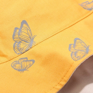 Détail du chapeau bob en toile jaune avec imprimé papillon gris et coutures soignées