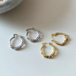 Macro shot of French style S925 silver knot earrings in gold and silver finish