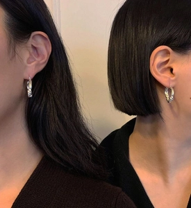 Detail of twisted silver hoop earrings shown on a model with long and short hair styles