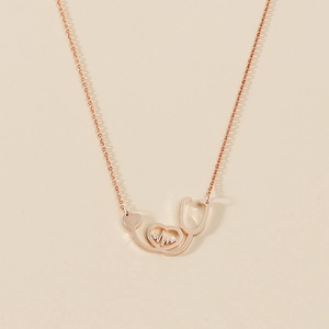 Detail of rose gold stethoscope heart necklace with pulse pendant and fine cross chain