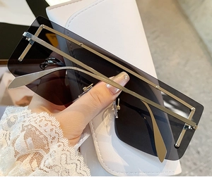 Detail of oversized rimless rectangular sunglasses with silver metal temples and grey lenses