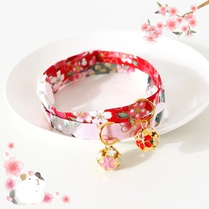 Close-up of pink and red floral pet collars with bells on a white decorative dish