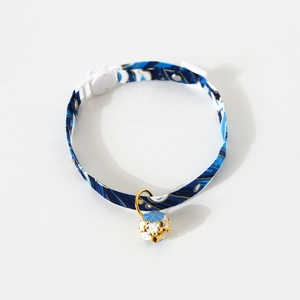 Close-up of blue Japanese wave pattern pet collar with white cat-shaped buckle and gold bell