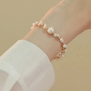 Bracciale di perle intrecciate con perline dorate indossato da una modella su sfondo giallo