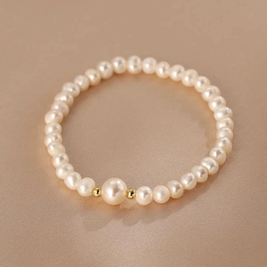 Elegant freshwater pearl bracelet with large center pearl on champagne silk backdrop