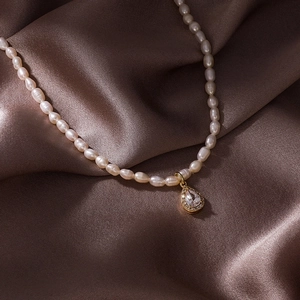 Detailed close-up of a baroque pearl necklace with a gold water drop pendant and zircon