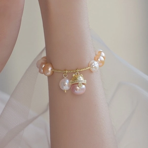 Detail of baroque freshwater pearl bracelet with gold lucky cat charm on wrist