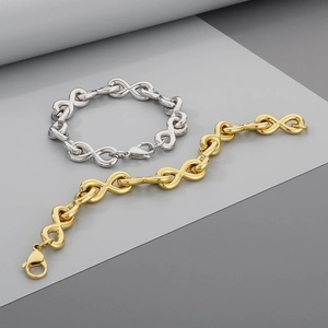 Macro detail of infinity symbol link bracelet in polished gold and silver finishes