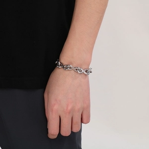 Close-up of a chunky silver stainless steel chain bracelet worn on a female wrist