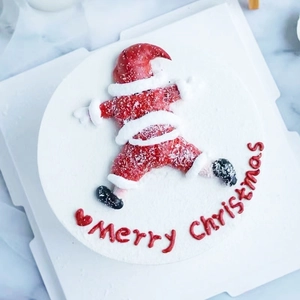 Top view of a soft PVC Santa Claus cake topper with Merry Christmas lettering on white cream