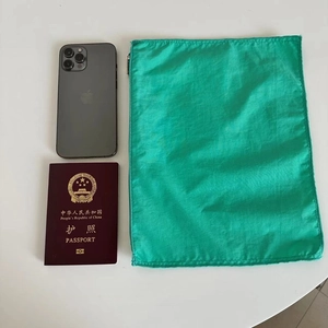 Portable green nylon organizer bag size comparison with a smartphone and a passport