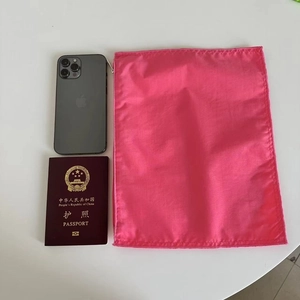 Detail view showing size of rose red nylon organizer pouch next to passport and smartphone