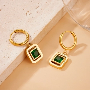 Vintage gold geometric drop earrings with square emerald stone on a stone surface