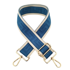 Close-up of blue and beige geometric jacquard strap with gold metal lobster clasps