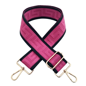 Detail of wide pink and black jacquard woven strap with golden metal lobster clasps