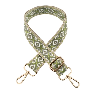 Close-up of green and beige ethnic geometric patterned wide bag strap with gold buckles