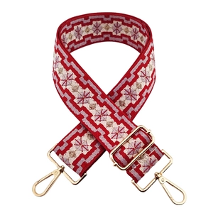 Close-up of red ethnic geometric jacquard bag strap with golden metal swivel hooks