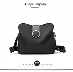 Front view of black nylon shoulder bag with a large metallic round buckle decoration
