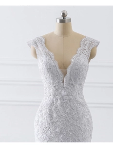 Detail of deep V-neckline with scalloped lace and sequins on white mermaid bridal gown