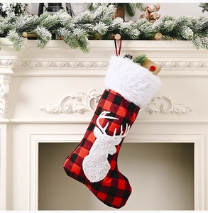 Détail de chaussette de Noël à carreaux rouges et noirs avec renne blanc et fausse fourrure