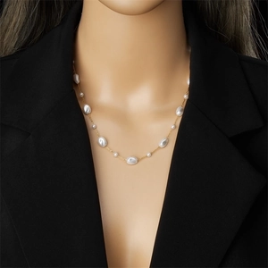 Baroque pearl and gold chain necklace shown on a model in professional lighting