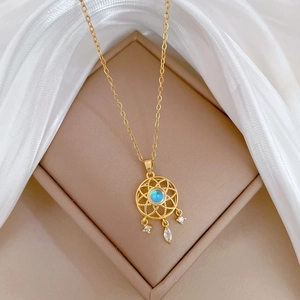 Gold dreamcatcher necklace with blue gemstone and sparkling crystals on silk background