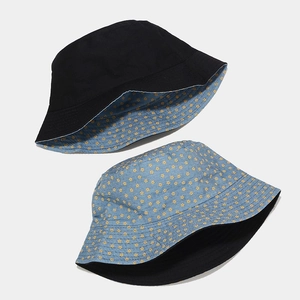 Detail of reversible bucket hat with black solid side and blue floral pattern design
