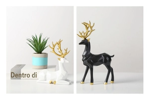 Close-up of geometric deer statues in white and black resin with elegant golden antlers