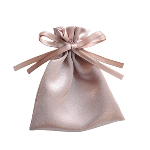 Glossy champagne satin drawstring gift bag with elegant silk ribbon bow on white background