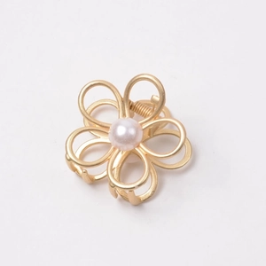 Macro shot of gold hollow flower hair claw clip with a white pearl center inlay