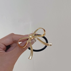 Close-up of golden metallic bow hair tie with high-elastic black rubber band for women