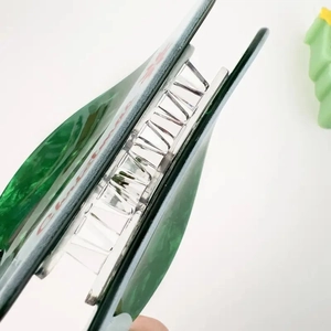 Green Christmas hat hair claw clip with a shark grip design shown from a side view angle