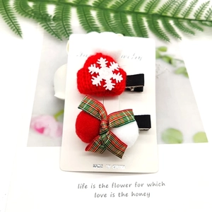 Detail of Christmas hair clips featuring mini knitted hat and plush pompom on a card