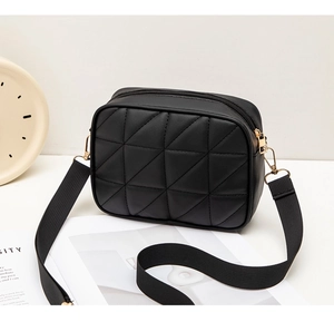 Detail view of black PU leather camera bag with quilted pattern and wide woven strap